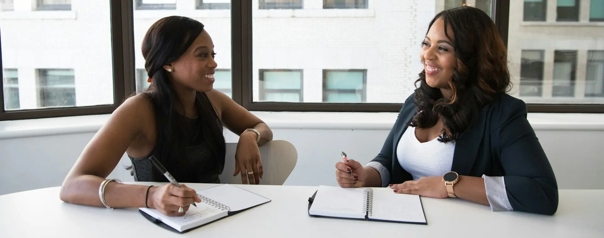 two women taking to each other while holding pens